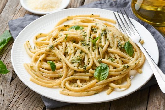 Pesto spaghetti pasta with basil, garlic, pine nuts, olive oil. Rustic table, side view, close up