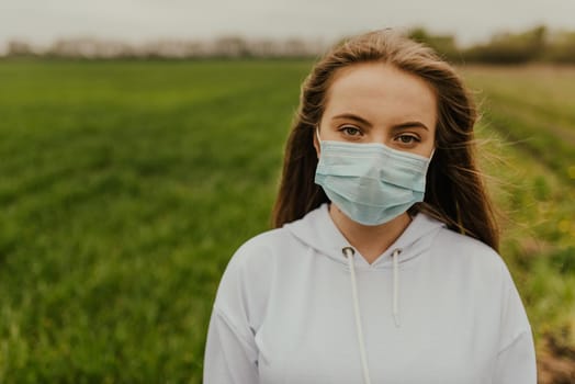 Young blond European woman in a protective mask outdoors.