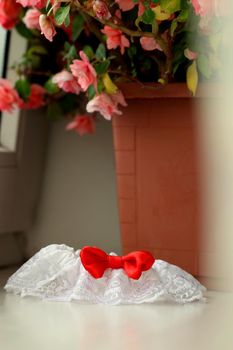 A white linen garter with a red bow.