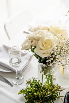 Wedding table set up in taditional style with roses grass and greenery. Close up of white roses bouquet