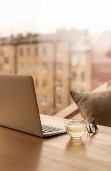 Freelance Desk with open laptop, cup of green tea and glasses on table. Cafe or coworking space. Concept of digital nomads, home office, blogging. No people. Vertical