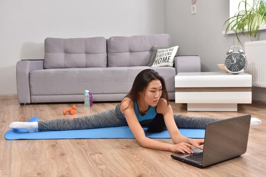 Young asian woman making yoga at home. Carantin and hobby. Home isolation. Online training. Soft focus