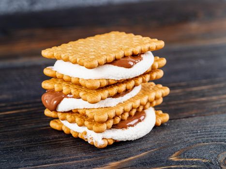 Smores, marshmallow sandwiches - traditional American sweet chocolate cookies on dark wooden table, side view
