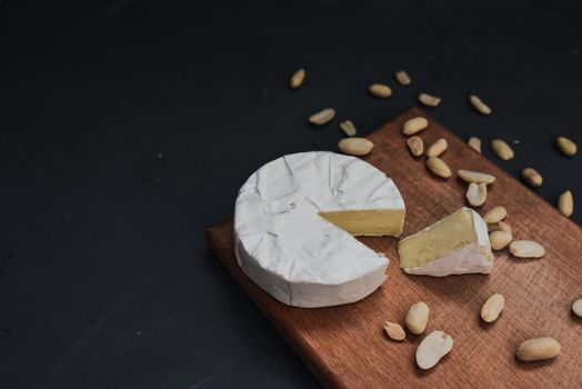 cheese camembert with mold and nuts on the wooden cutting board