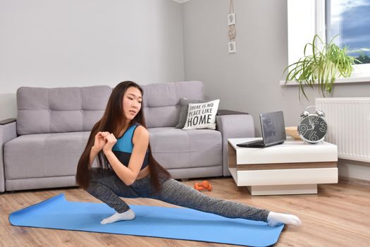 Young asian woman making yoga at home. Carantin and hobby. Home isolation. Online training. Soft focus