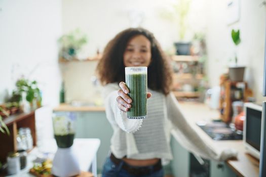 Girl showing her green smoothie at camera