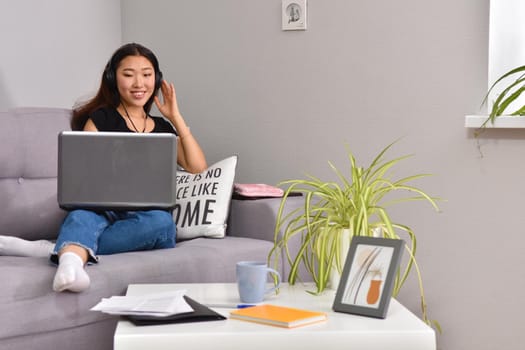 attractive asian young woman working with laptop and listening music at home