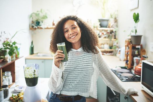 Portrait of a young african girl smiling at camera with a smoothie in her hand