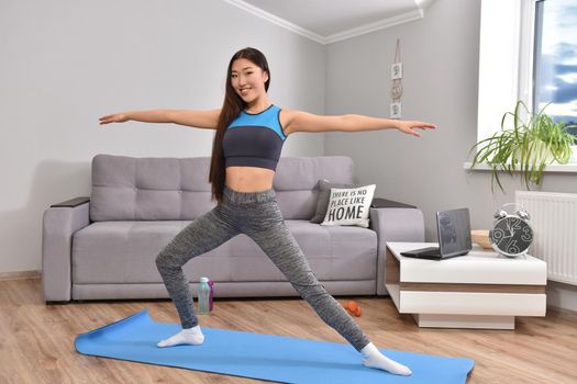 Young asian woman making yoga at home. Carantin and hobby. Home isolation. Online training. Soft focus