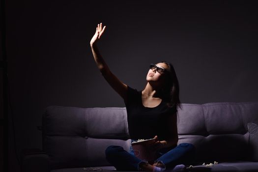 Beautiful young Asian woman watching TV at home. Eating popcorn. Time at home, isolation