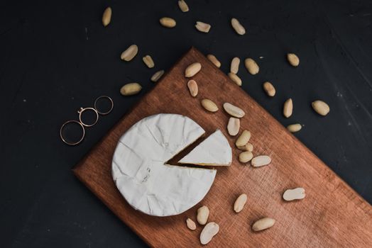 cheese camembert with mold and nuts and wedding rings on the wooden cutting board