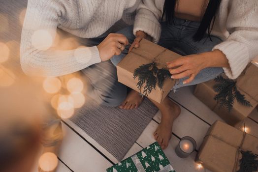 Christmas morning. New Year's interior. Valentine's Day celebration. husband and wife open Christmas gifts barefoot near the Christmas tree. craft boxes. garland lights. new year 2021