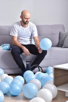 Celebration, holidays, party concept. Happy hairless man preparing to party. Blowing blue and white balloons