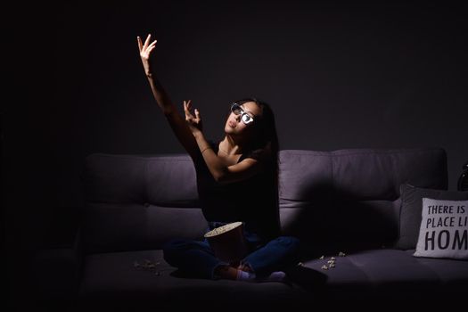 Beautiful young Asian woman watching TV at home. Eating popcorn. Time at home, isolation