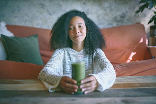 Portrait of you african girl smiling at camera with smoothie in her hand