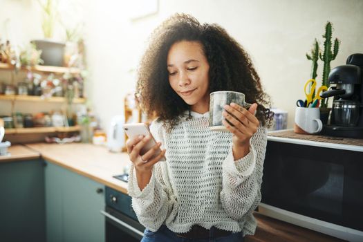 Beautiful young african girl enjoying coffee and social media in her kitchen