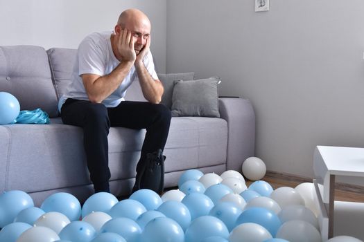 Celebration, holidays, party concept. Happy hairless man preparing to party. Blowing blue and white balloons