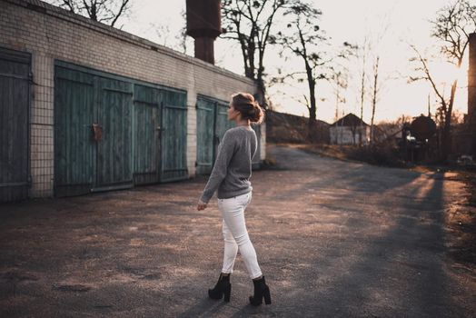 beautiful young blonde model girl smile. gray knitted sweater. On the Sunset. Portrait. hair tied in a bun