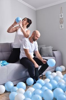 Family couple blowing white and blue balloons. Man and woman preparing before party