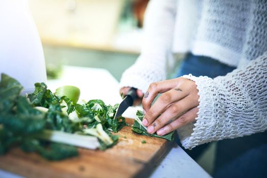 Cropped shot of a young woman making a healthy snack with spinach at home. High quality photo