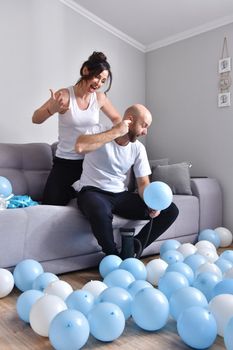Family couple blowing white and blue balloons. Man and woman preparing before party