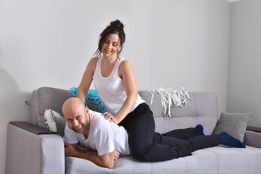 Photo of cheerful romantic caucasian family couple smiling and hugging while sitting on sofa at home. Man and woman in love