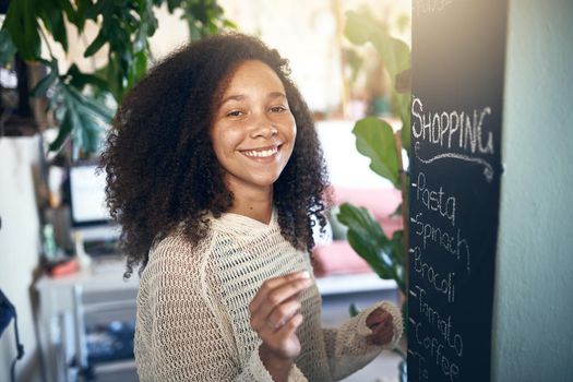 Beautiful young girl smiling at camera while making a shopping list. High quality stock photo