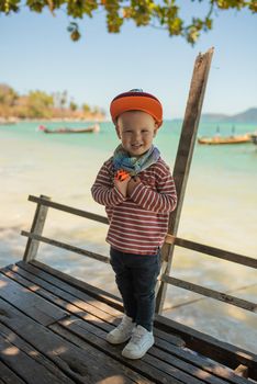 Fashion child. Happy boy model. Stylish little boy in baseball. Handsome kid. White Sneakers. red cap.Aquamarine sea background