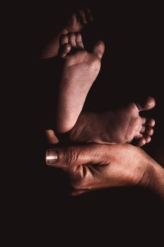 Baby feet held by loving mother in black and white. High quality photo