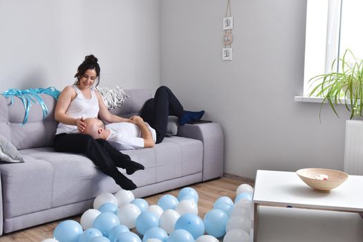 Photo of cheerful romantic caucasian family couple smiling and hugging while sitting on sofa at home. Man and woman in love