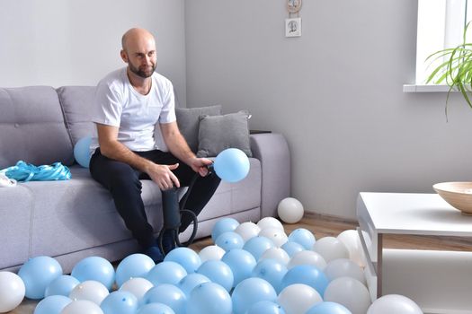 Celebration, holidays, party concept. Happy hairless man preparing to party. Blowing blue and white balloons