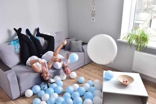 Family couple blowing white and blue balloons. Man and woman preparing before party