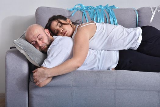 Photo of cheerful romantic caucasian family couple smiling and hugging while sitting on sofa at home. Man and woman in love