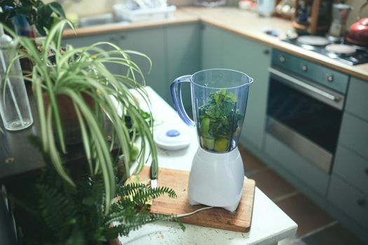 Still shot of blender with greens in a beautiful kitchen