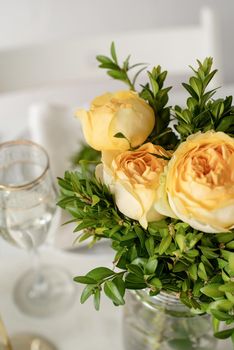 Wedding table set up in taditional style with roses grass and greenery. Close up of beige roses bouquet