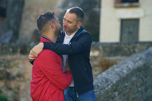 Cheerful loving couple of homosexual males hugging in street and looking at each other