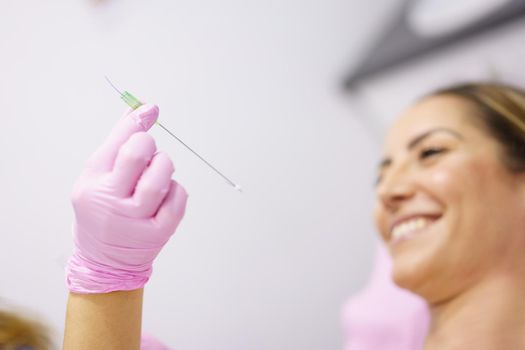 Doctor showing a PDO treatment suture thread to her patient. Middle-aged woman.