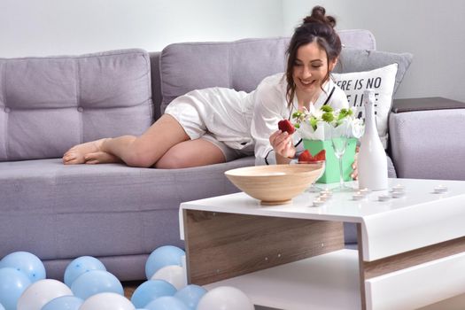 Beautiful brunette woman dressing gown with bouquet indoors. Female portrait in living room