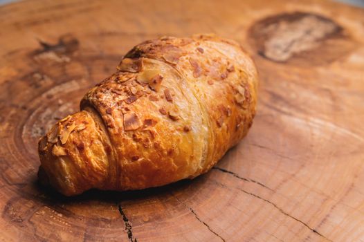 Close-up of a delicious croissant with almonds on a wooden pallet. Delicious and healthy breakfast.