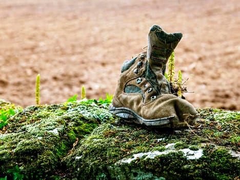 An old discarded trekking boot on a stone