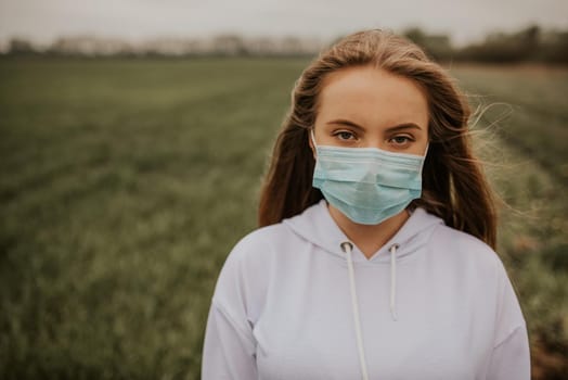 Young blond European woman in a protective mask outdoors.