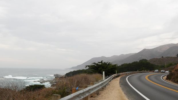 Pacific coast highway 1, Cabrillo road along ocean, foggy California, Big Sur, USA. Coastal road trip, traveling on car by sea. Cloudy misty weather. Yellow dividing line, asphalt. Turn of serpentine.