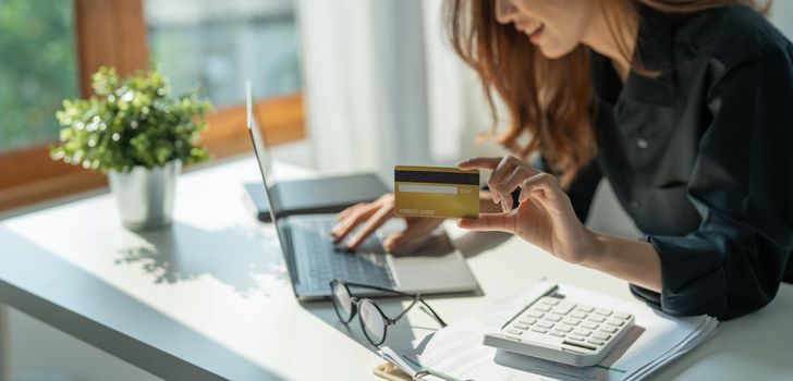 Close up of girl hold bank credit card and type on laptop, shopping online using computer, buying goods or ordering online, entering bank accounts and details in online banking offer