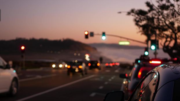 Defocused traffic lights, pacific coast highway 1, Torrey Pines state beach, Del Mar, San Diego, California USA. Road trip vacations. Roadtrip along ocean, freeway 101. Cars in evening twilight dusk.