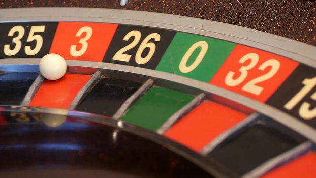 Ball on wooden french roulette table in casino. Wheel spinning, turning or rotating. Odd and even numbers, black, red and zero sectors. Bets in game of chance. Money playing, gambling or risky betting