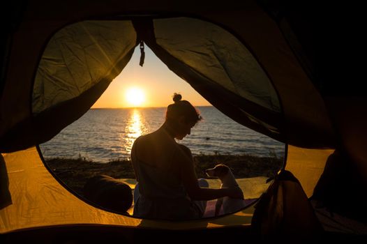 Woman and dog in a tourist tent at sunset. Camping with a pet.