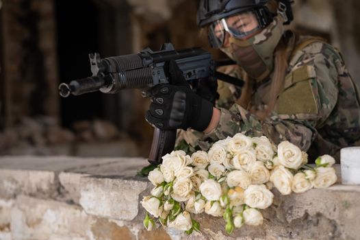 Caucasian woman in military uniform holding a machine gun and a bouquet of white roses