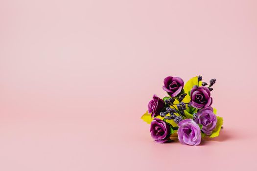 Artificial purple rose bouquet on pink background for love and Valentine's day concep