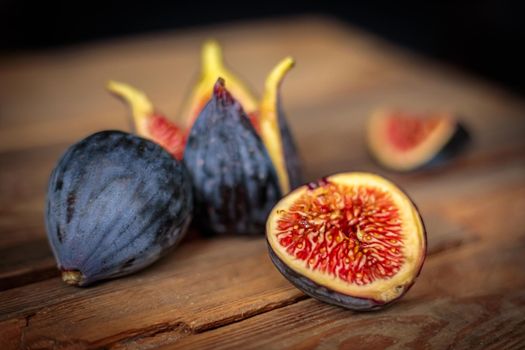 Fresh cut purple figs on a wooden background from old boards. Raw exotic figs. Low key