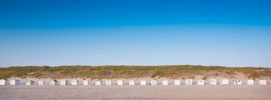 beach huts on dutch wadden island of texel at dusk under blue sky in summer in the netherlands